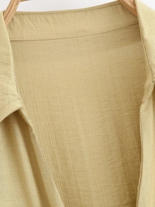 Detail of a khaki linen shirt featuring a crisp collar and textured woven fabric texture