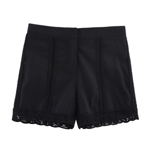 Detail of high-waisted black shorts with lace crochet trim and vertical cutout stripes