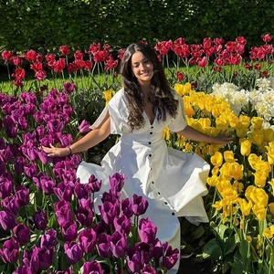 Detail of white V-neck dress with black buttons in a colorful tulip garden field