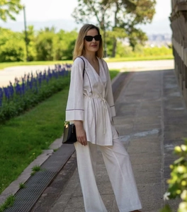 Detailed close-up of white tied top with black contrast piping and matching wide-leg trousers
