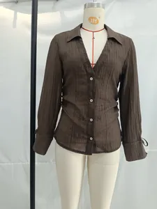 Detail eines braunen V-Ausschnitt-Plisseeshirts mit Kordelzugmanschetten und Transparenz