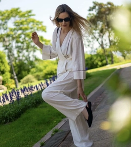 Detail view of white linen two-piece set with dark stripe trim and waist tie closure