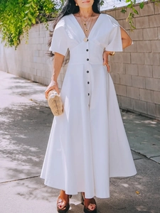 Detail of white V-neck midi dress featuring contrast black buttons and a cinched waistline