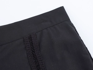Detail of black cotton fabric featuring intricate vertical crochet lace and neat stitching