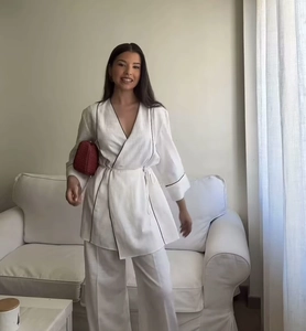 Detail of white wrap top with black piping and matching wide-leg pants on model