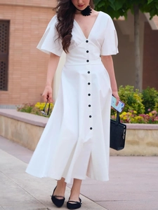 Detail of white V-neck dress with decorative contrast buttons and elegant waistline