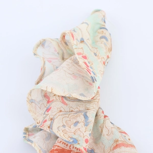Dettaglio di sciarpa trasparente con stampa paisley, bordo arrotolato e colori vivaci