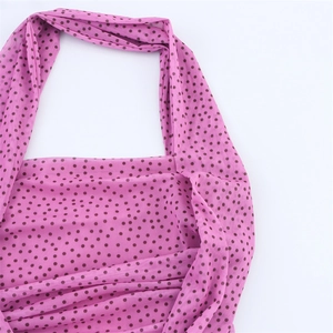 Dettaglio dell'abito in chiffon rosa a pois con scollatura arricciata e trama morbida