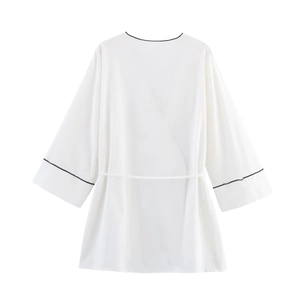 Detailed close-up of white wide-leg pants with black contrast piping and soft fabric texture
