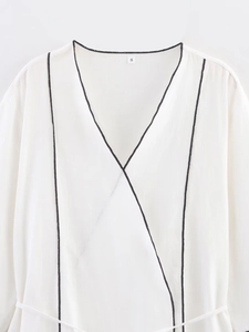 Detail of white wrap top neckline with black piping and size S tag on collar