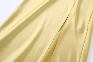 Détail d'une robe en satin jaune clair montrant la fente latérale et la texture soie