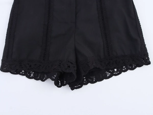 Detail of black slim-fit shorts featuring crochet lace hems and vertical lace inserts