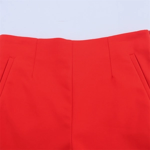 Detailed macro view of red high-waisted shorts featuring side pockets and fine stitching