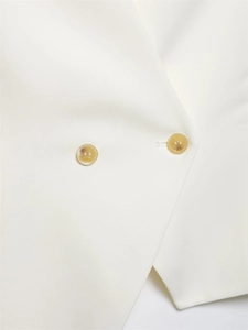 Close-up of white asymmetric vest collar featuring amber resin buttons and textured fabric