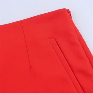 Detailed close-up of high-waist red trousers featuring a side zipper and side pockets