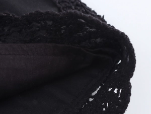 Detailed macro view of black fabric featuring intricate crochet lace trim and woven texture