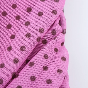 Macro di tessuto a rete rosa con pois marroni che mostra la trama dettagliata