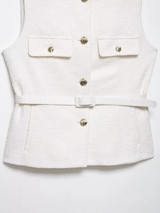 Dettaglio del gilet in tweed bianco con bottoni dorati in rilievo e cintura testurizzata