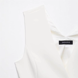 Detail shot of the V-neckline with high-quality stitching on this white asymmetric vest
