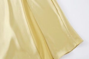 Détail d'une robe en satin jaune clair montrant la texture soyeuse et l'ourlet soigné