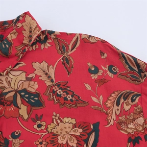 Close-up of vintage floral print detail on vibrant red long-sleeve blouse for women
