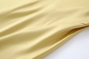 Détail d'une robe en satin jaune clair montrant la poche latérale et la texture soyeuse
