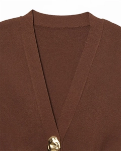 Macro shot of V-neck knit vest featuring a gold molten-textured artistic button detail
