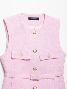 Dettaglio del gilet in tweed rosa con bottoni dorati, trama in rilievo e cintura abbinata
