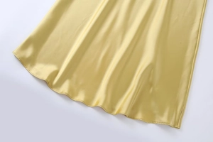 Détail de l'ourlet de la robe en satin champagne montrant le tissu brillant et le drapé