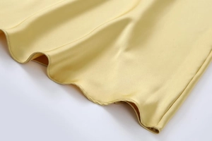 Vue détaillée de l'ourlet ondulé asymétrique sur le tissu en satin de couleur champagne