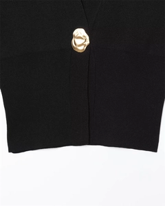 Close-up of black knit fabric featuring a decorative liquid-gold wavy metal button