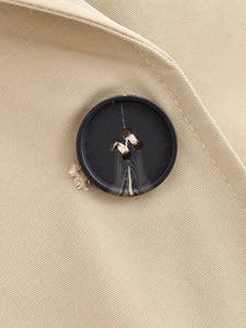 Macro detail of marble-textured button on khaki twill fabric of a minimalist jacket