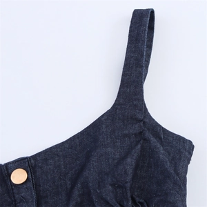 Detailed close-up of dark denim fabric texture with thick strap and gold button accent