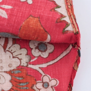 Detailed close-up of neat stitching on a red floral print cotton fabric garment