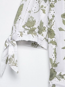 Dettaglio di manica in cotone bianco con stampa floreale, ricamo traforato e nodo delicato