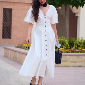 Elegant white V-neck dress with decorative black buttons and flowing flare sleeves