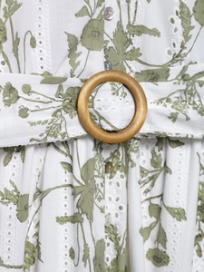 Dettaglio vestito ricamato a fiori con fibbia in legno e bottoni di perle eleganti