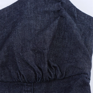 Detailed macro shot of gathered stitching and texture on dark blue denim midi dress