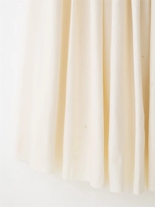Detailed close-up showing the natural cream cotton linen fabric texture and vertical pleats