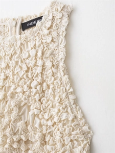 Close-up of cream-colored dress featuring textured 3D pleats and back zipper detail