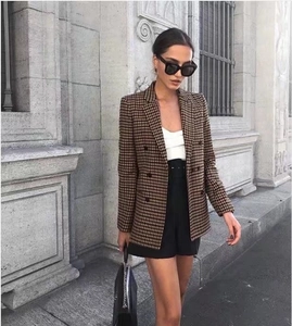 Detail of double-breasted houndstooth blazer featuring refined texture and street style