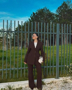 Detailed view of dark brown slim-fit suit jacket with matching flared trousers on model