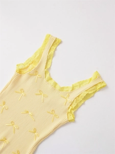 Detail der Rippstrick-Struktur mit Minischleifen und Spitzenbesatz an gelbem Camisole
