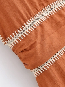 Detailed macro view of orange-brown textured fabric with white hollow embroidery