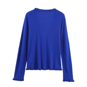 Detail of royal blue knitted top with delicate ruffled edges on cuffs and hemline