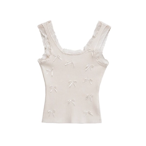 Detail eines weißen Rippstrick-Tops mit Spitzenbesatz und zarten Satin-Schleifen