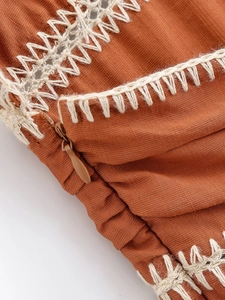 Detailed macro view of rust red fabric with white embroidery and matching invisible zipper