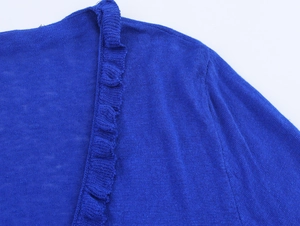 Detail of royal blue fine knit fabric with elegant ruffled edges and wavy trim