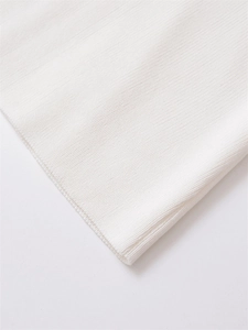 Macro view of white ribbed knit fabric detailing the soft texture and neat stitching