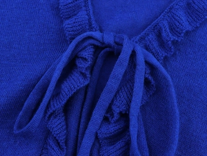Detail of royal blue knitted cardigan with delicate ruffle trim and tie closure